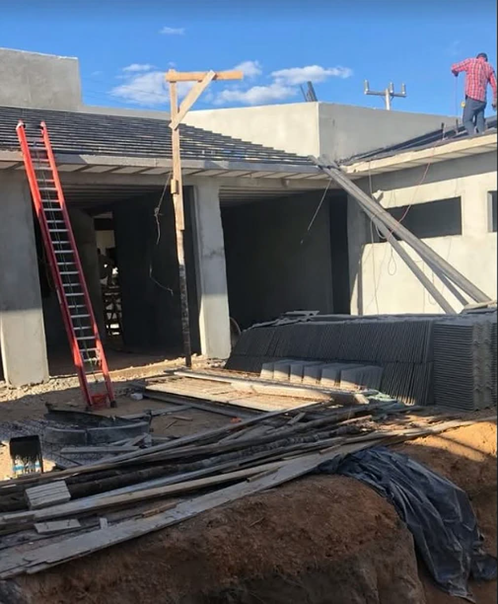 Obra da ArqEng em andamento: casa térrea com pilares de concreto, telhado sendo montado e escada encostada na estrutura.